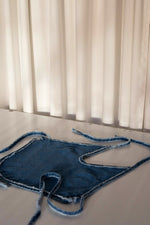 Halter denim top with rounded hem and adjustable waist with lacing in back. This white denim halter top has been crafted with contrast stitching in a toasted ocre color. 